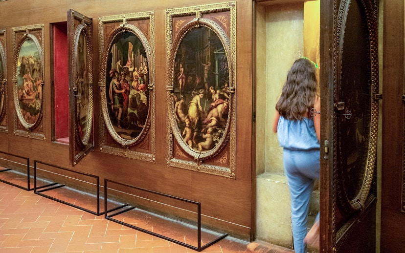 Palazzo Vecchio tour participant entering secret passage behind paintings.