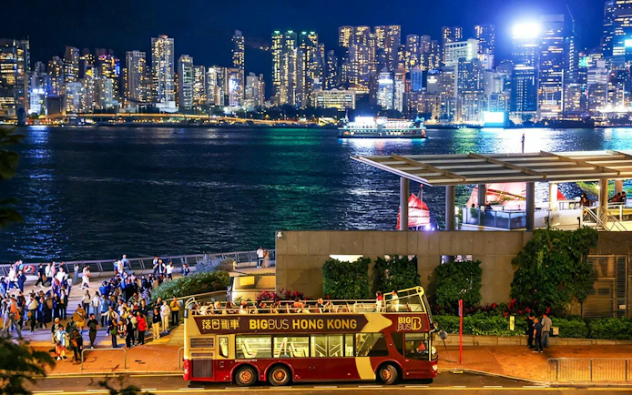 Big Bus tour in Hong Kong with Kowloon skyline at night.