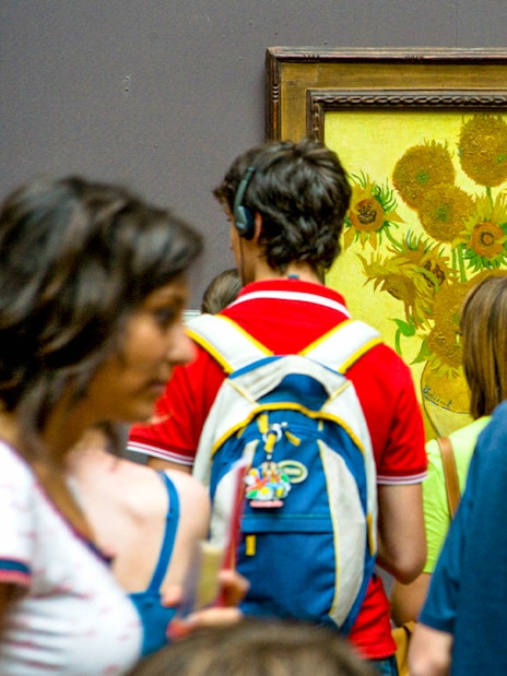 Visitors viewing Van Gogh's Sunflowers painting in a museum.