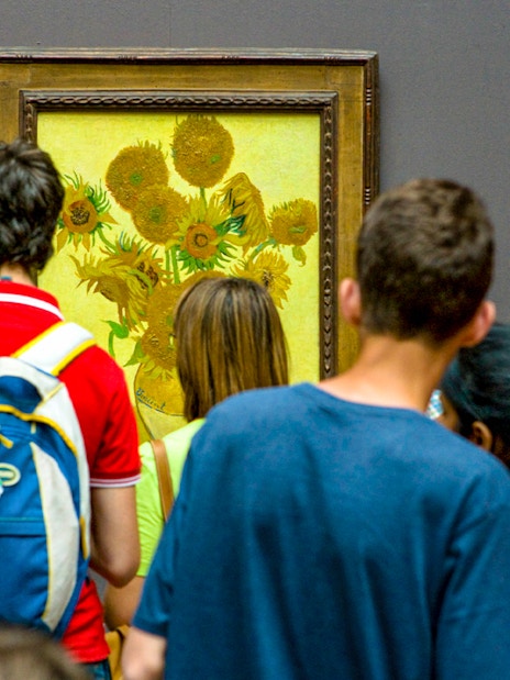 Visitors viewing Van Gogh's Sunflowers painting in a museum.