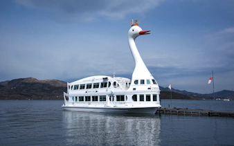 Swan-shaped cruise boat on Lake Yamanaka with mountains in the background.