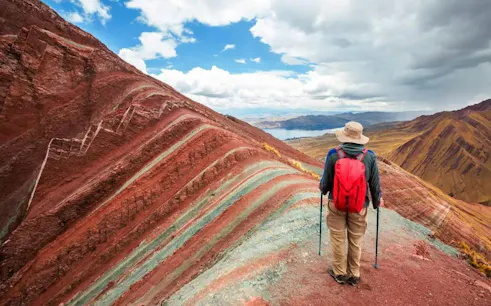 Hiker with red backpack on Pallay Punchu mountain trail near Cusco, Peru.