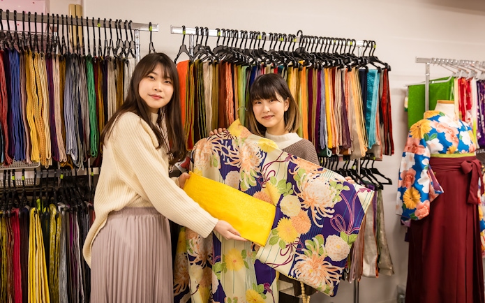 Guests selecting kimonos at Kyoto Kimono Rental with colorful fabric display.
