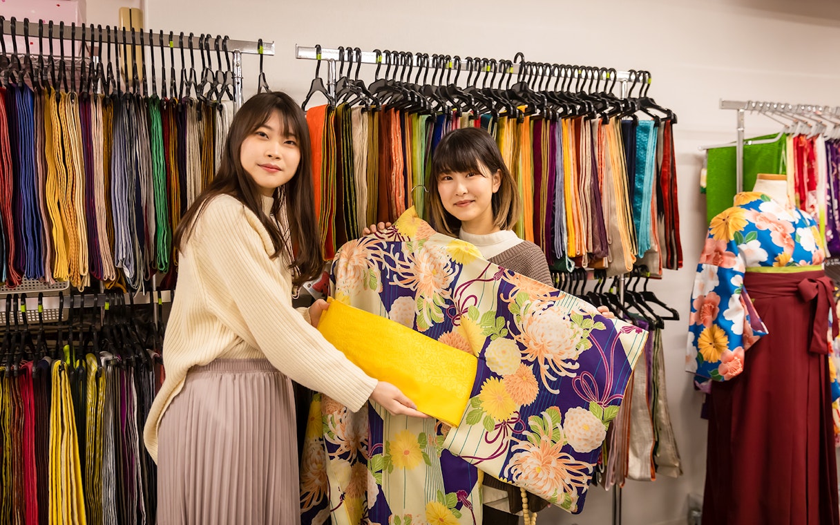 Guests selecting kimonos at Kyoto Kimono Rental with colorful fabric display.