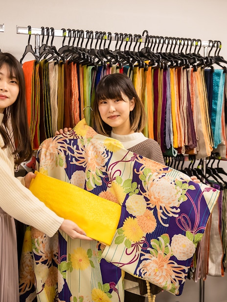 Guests selecting kimonos at Kyoto Kimono Rental with colorful fabric display.