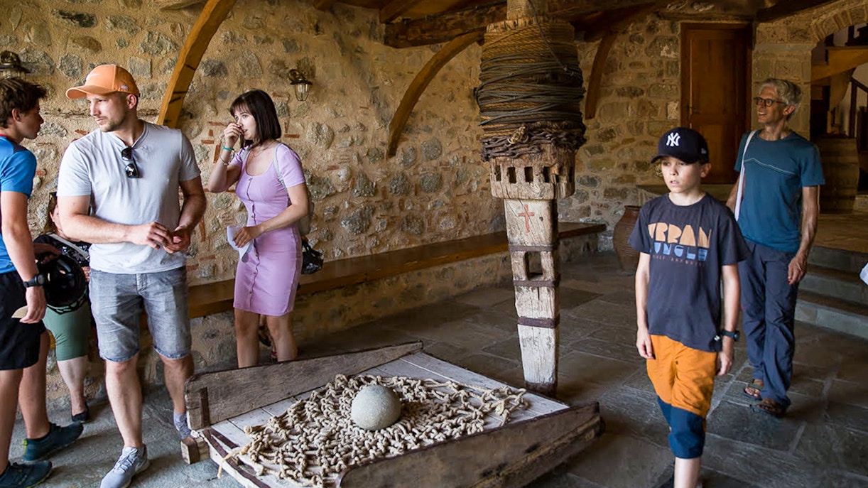 Tourists exploring inside Meteora Monastery, observing historical artifacts.