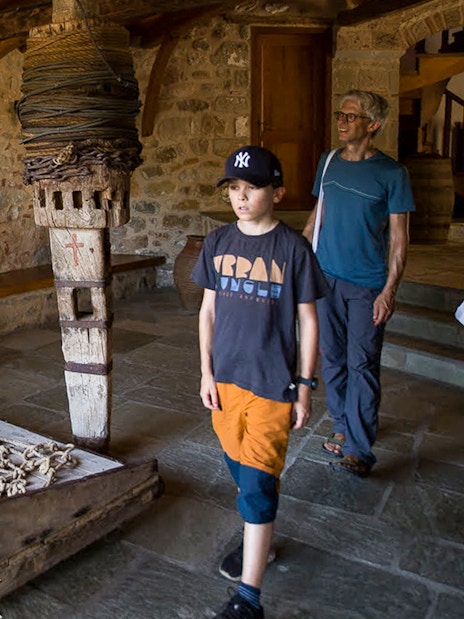 Tourists exploring inside Meteora Monastery, observing historical artifacts.
