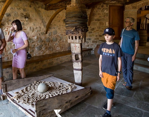 Tourists exploring inside Meteora Monastery, observing historical artifacts.