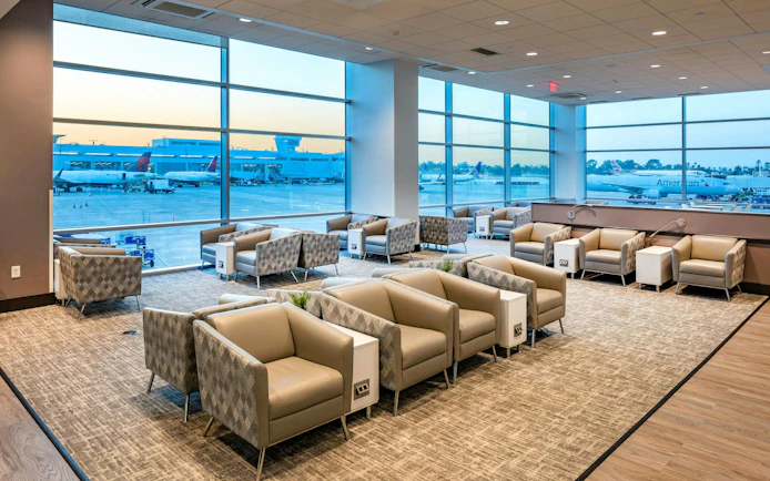 Aspire Lounge seating area with airport runway view at San Diego International Airport.