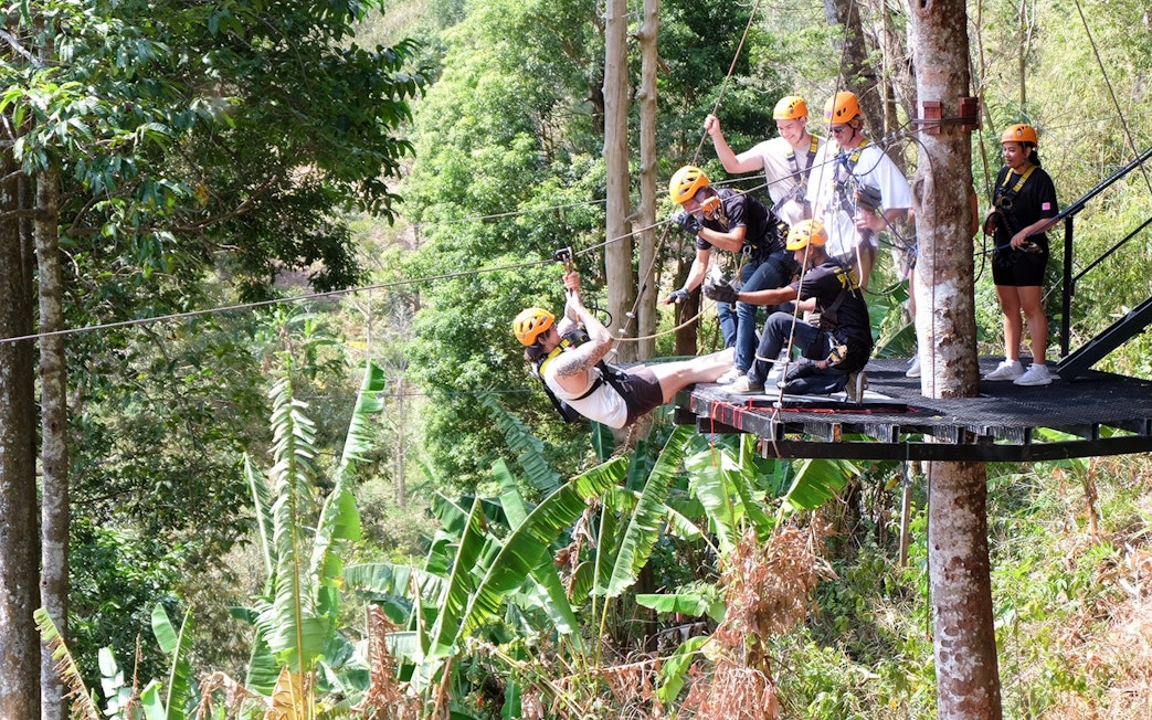 Participants ziplining through lush forest at Phuket Paradise.
