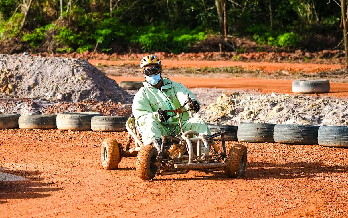 Person driving a go-kart on a dirt track at Batam Adventure Park.