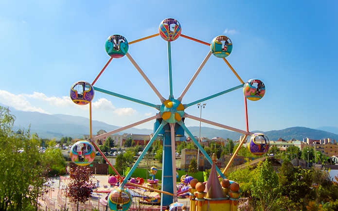 Ferris wheel at the entrance of MagicLand Amusement Park with colorful cabins.