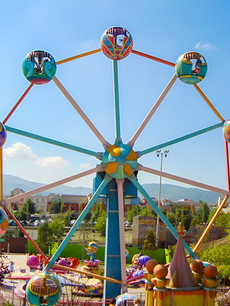 Ferris wheel at the entrance of MagicLand Amusement Park with colorful cabins.