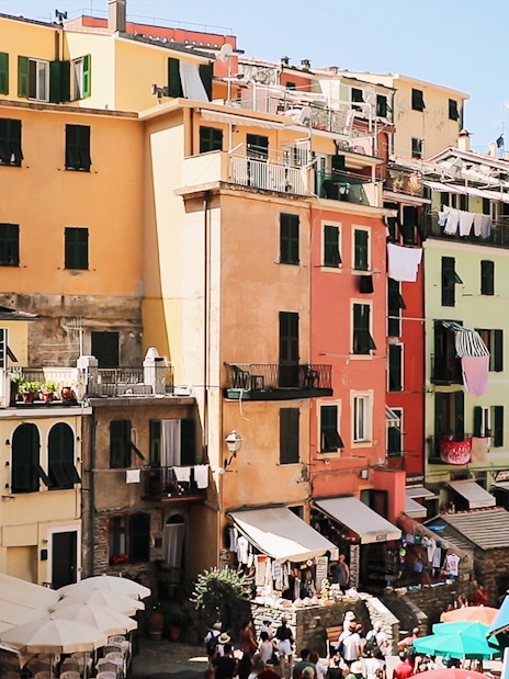 Colorful buildings in Vernazza, Cinque Terre, with tourists exploring the narrow streets.