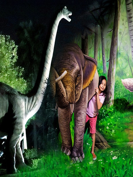 Children interacting with dinosaur and animal sculptures at Dubai Garden Glow.