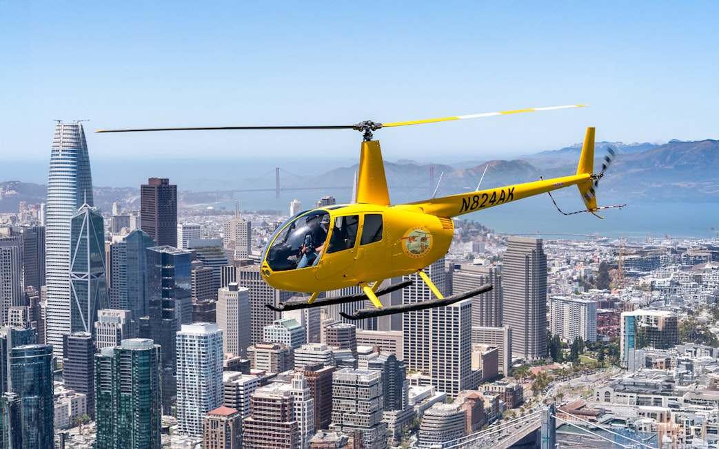 Helicopter flying over downtown San Francisco with Golden Gate Bridge in view.