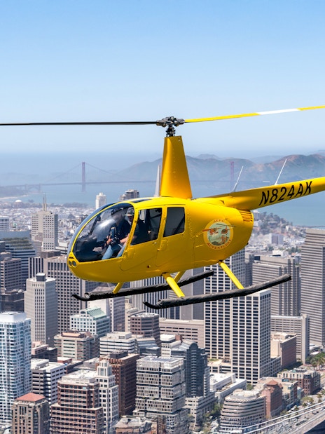 Helicopter flying over downtown San Francisco with Golden Gate Bridge in view.