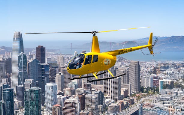 Helicopter flying over downtown San Francisco with Golden Gate Bridge in view.