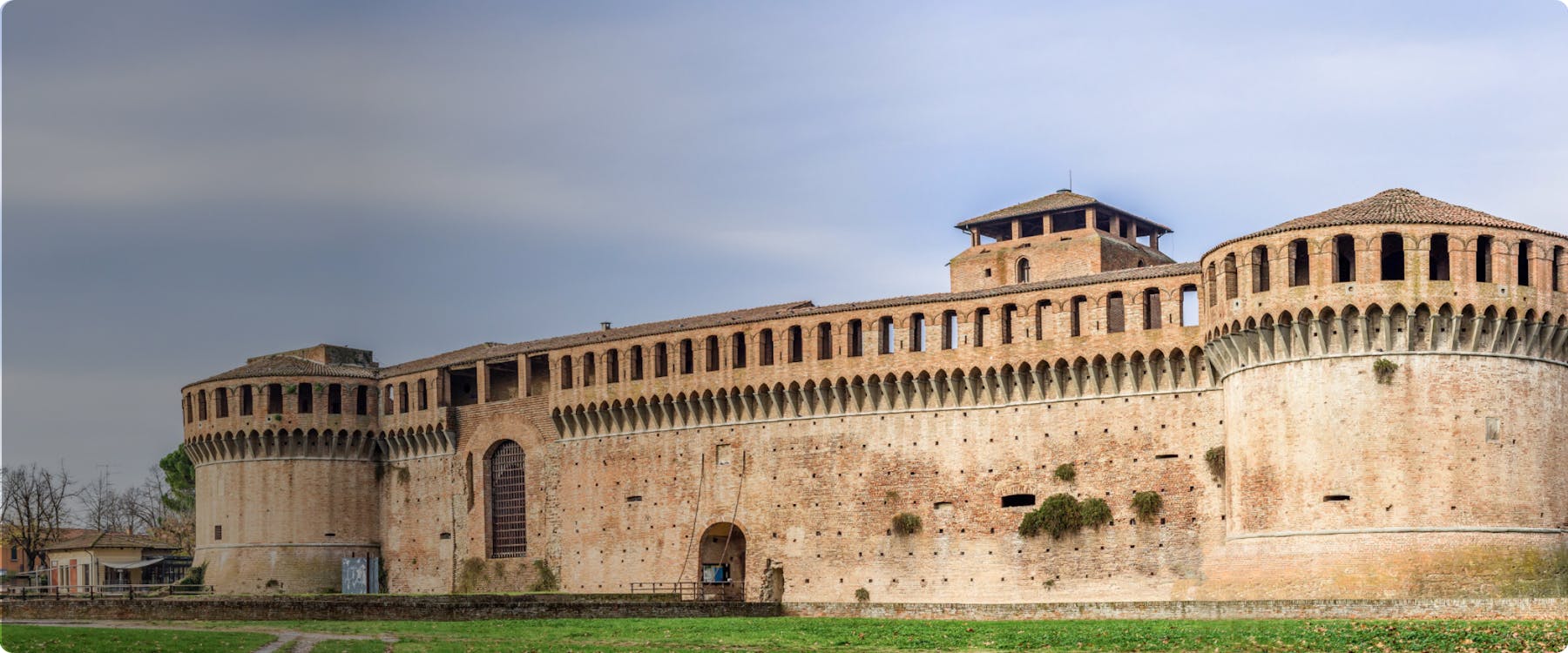 Medieval fortress in Imola, Italy, with brick walls and round towers.