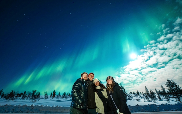 Northern Lights over snowy landscape with group on Tromso tour.