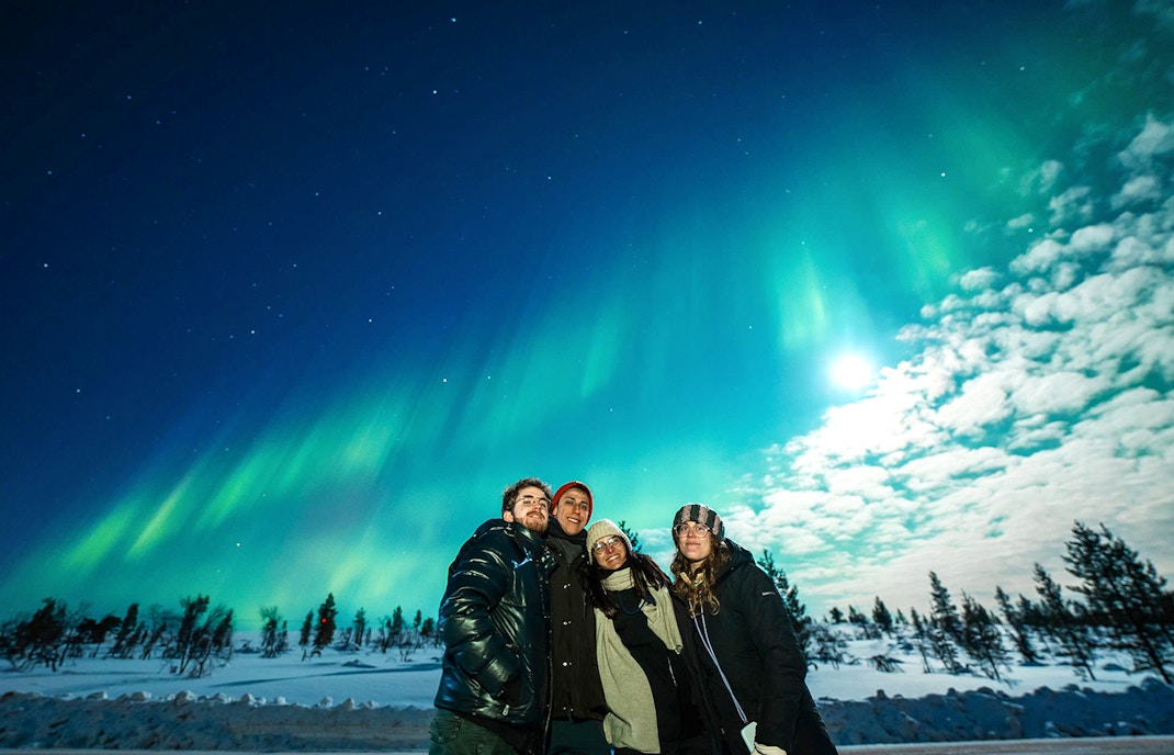 tourists observing northern lights visible in beautiful night sky over tromso