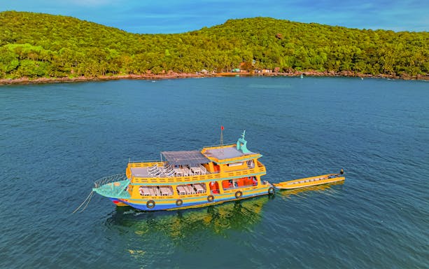 Boat on Red River for 3 Island Hopping Tour with lush green hills in the background.
