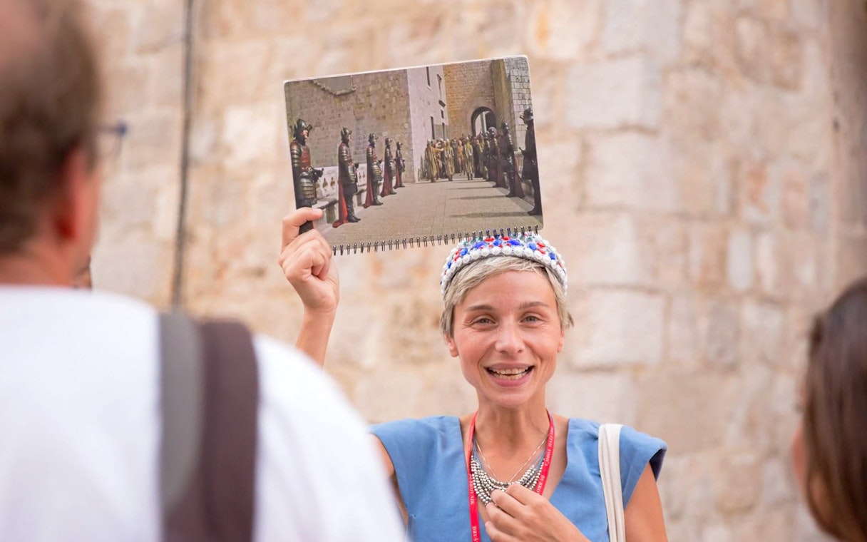 Tour guide in Dubrovnik holding a Game of Thrones scene photo during a walking tour.