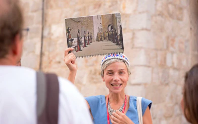 Tour guide in Dubrovnik holding a Game of Thrones scene photo during a walking tour.