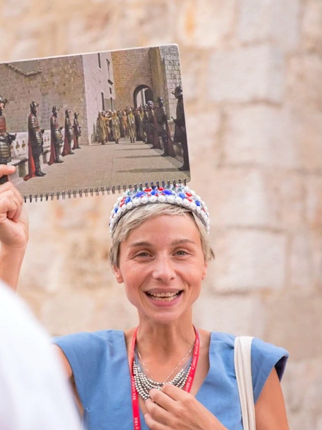 Tour guide in Dubrovnik holding a Game of Thrones scene photo during a walking tour.