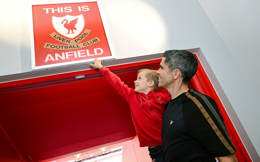 Guests at Anfield players tunnel touching the "This is Anfield" sign.