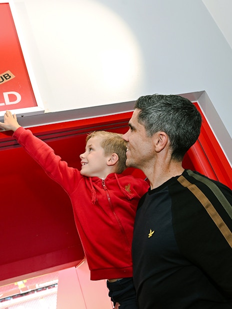 Guests at Anfield players tunnel touching the "This is Anfield" sign.