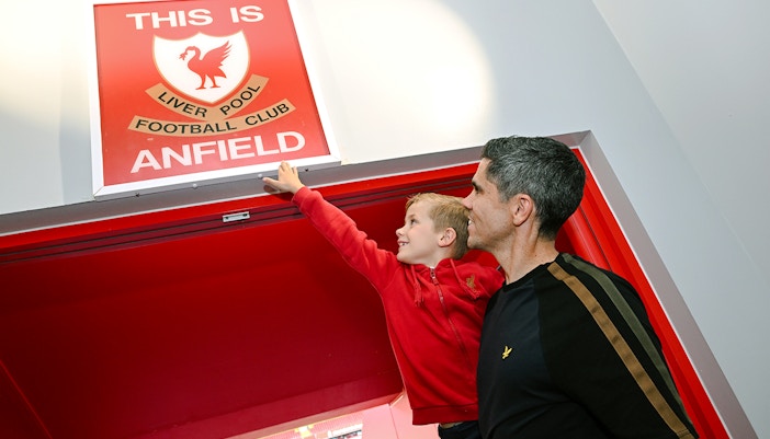 Guests at Anfield players tunnel touching the "This is Anfield" sign.