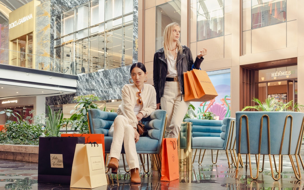 Guests with shopping bags at American Dream mall near luxury stores.