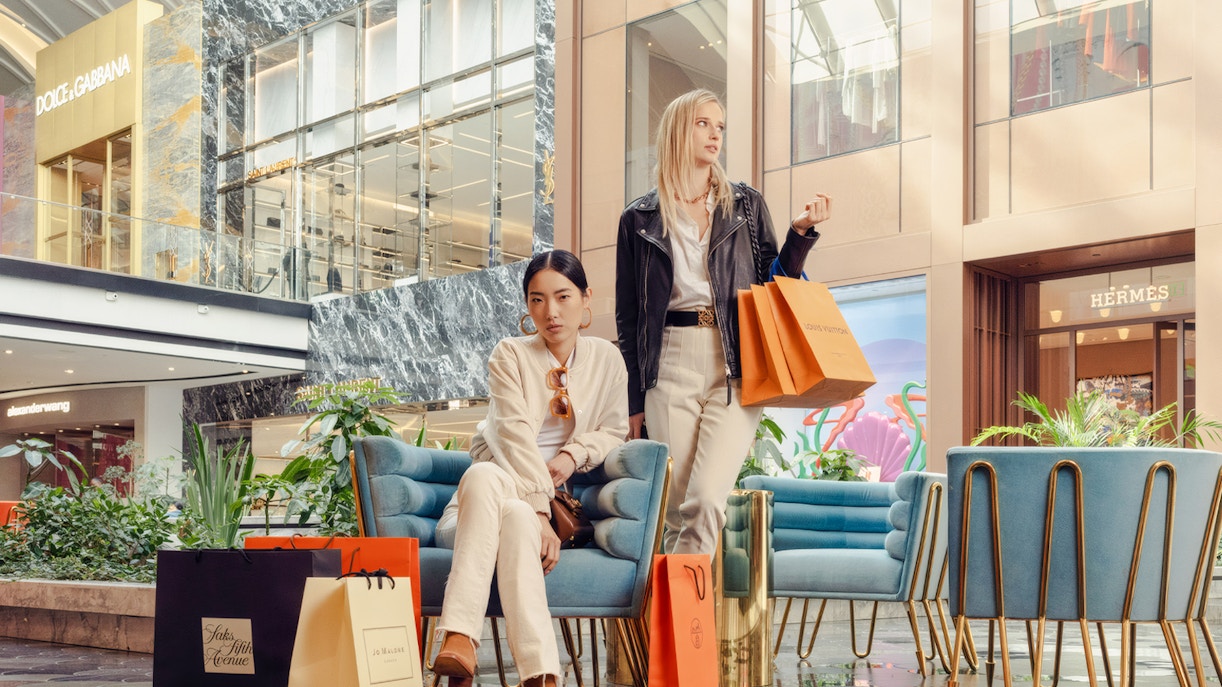 Guests with shopping bags at American Dream mall near luxury stores.
