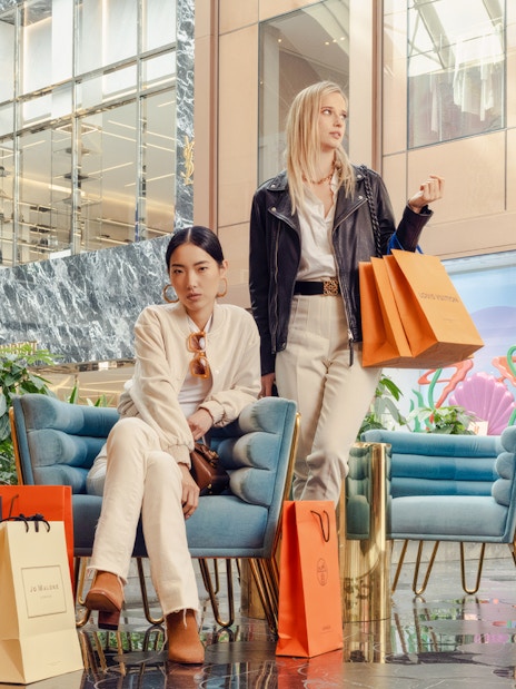 Guests with shopping bags at American Dream mall near luxury stores.