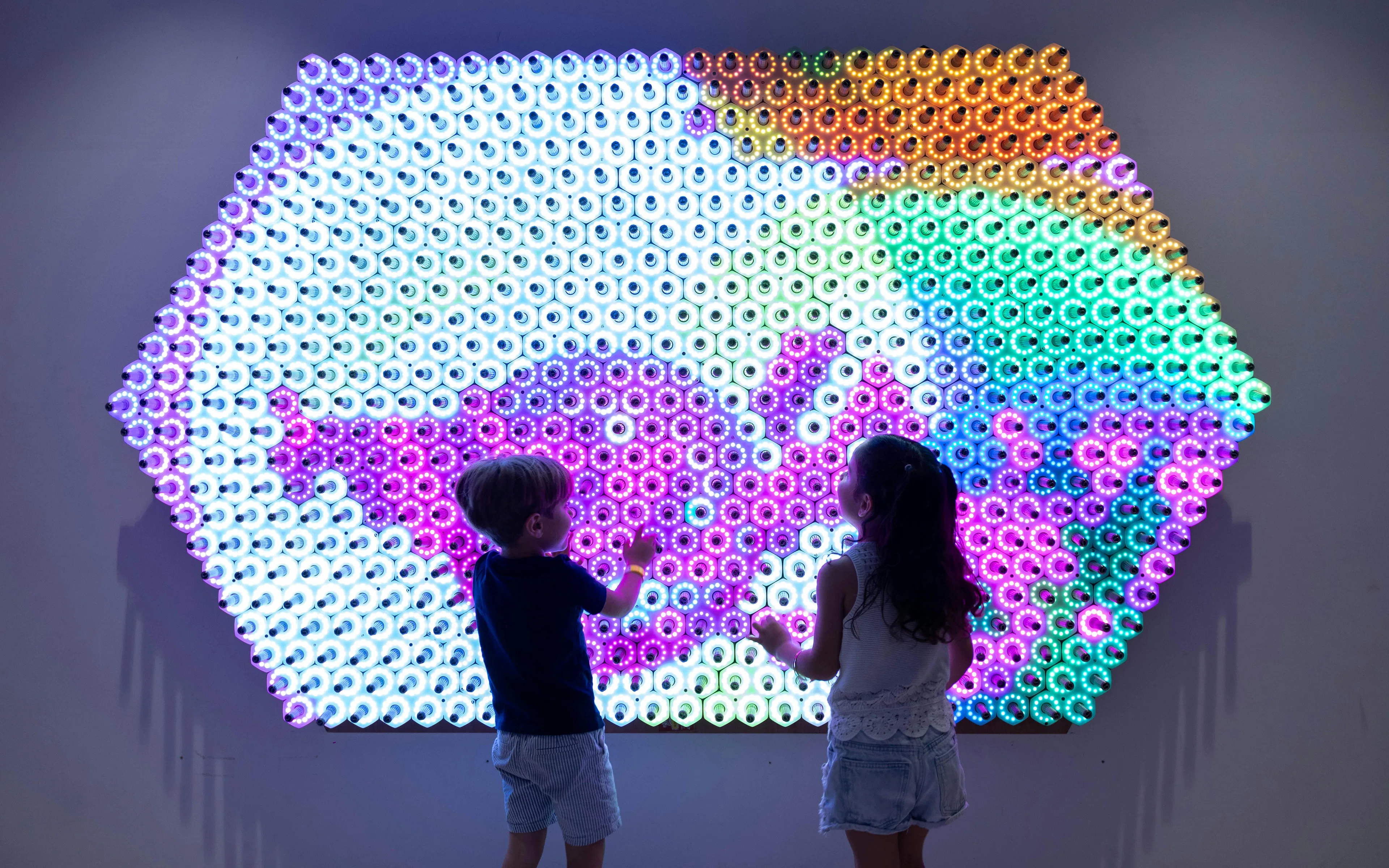 Children interacting with a colorful light wall at OliOli Children's Museum.