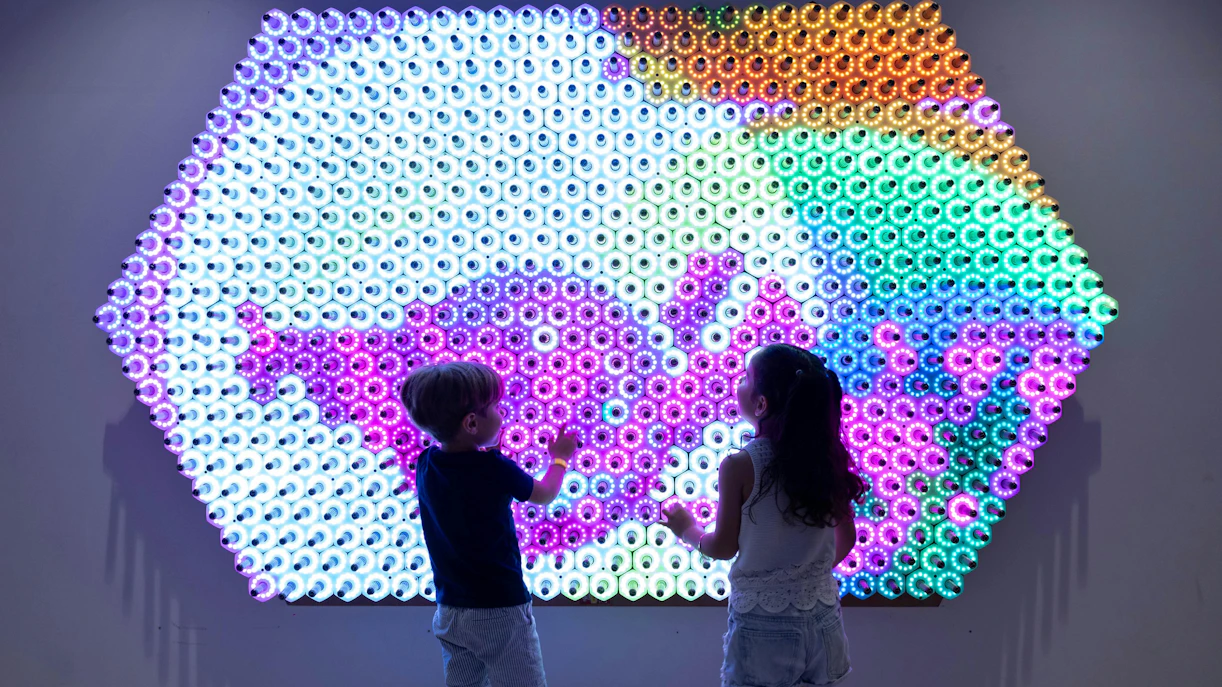 Children interacting with a colorful light wall at OliOli Children's Museum.