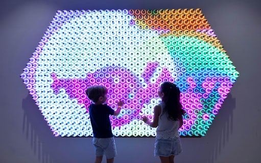 Children interacting with a colorful light wall at OliOli Children's Museum.