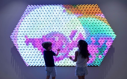 Children interacting with a colorful light wall at OliOli Children's Museum.