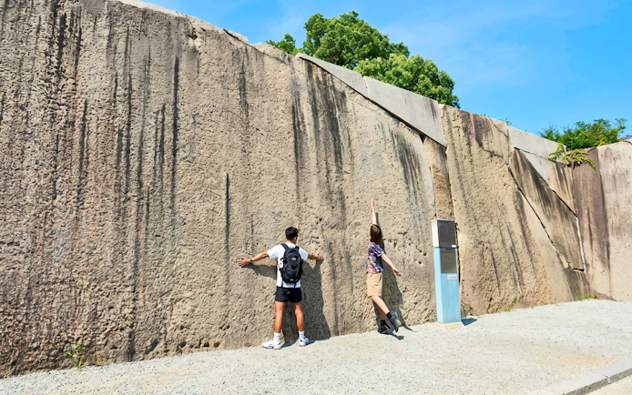 Visitors standing by the Octopus Stone near Sakura Gate at Osaka Castle, Japan.