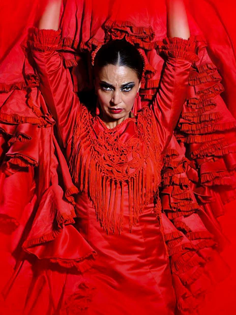 Flamenco dancer performing at Teatro Flamenco Madrid in a vibrant red dress.