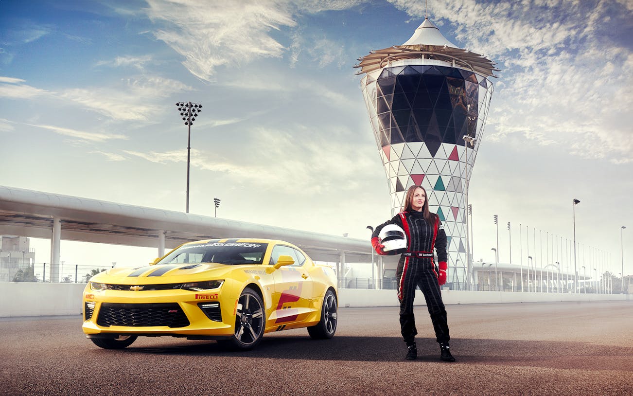 Chevrolet Camaro SS at Yas Marina Circuit with driver in racing suit holding helmet.
