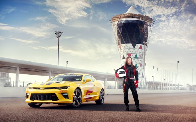 Chevrolet Camaro SS at Yas Marina Circuit with driver in racing suit holding helmet.