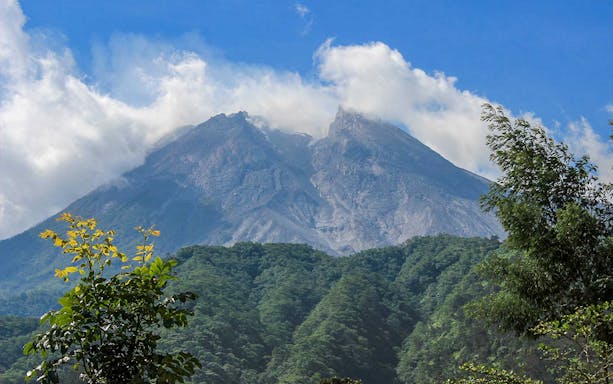 Merapi volcano with lush greenery and clouds, part of Setumbu Sunrise tour.