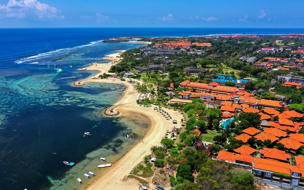 Aerial view of Tanjung Benoa coastline in Bali with boats and coral reefs.