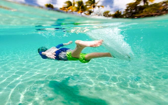 Child swimming underwater in clear ocean near Cancun.