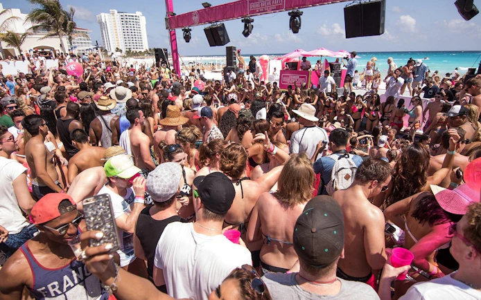 Crowd enjoying a lively beach party at Mandala Beachclub Cancun.