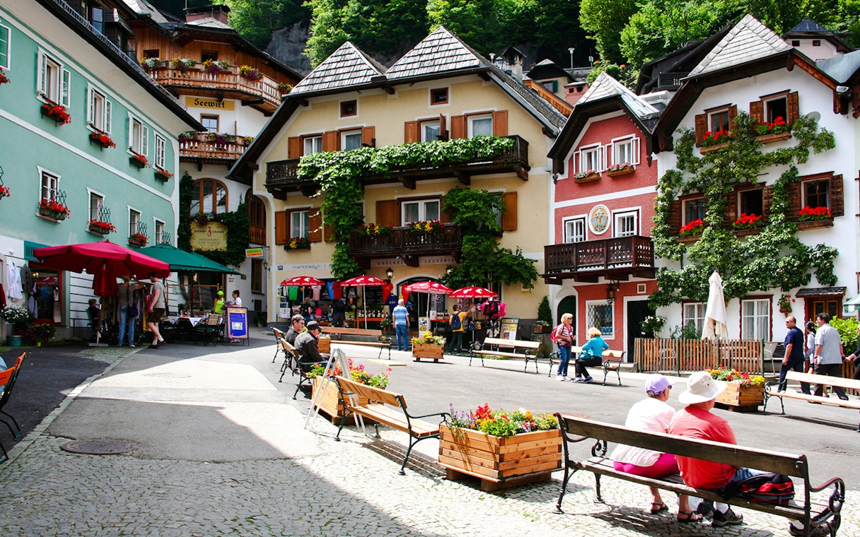 Hallstatt old town square with colorful buildings and people sitting on benches, Austria.