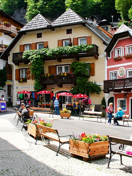 Hallstatt old town square with colorful buildings and people sitting on benches, Austria.