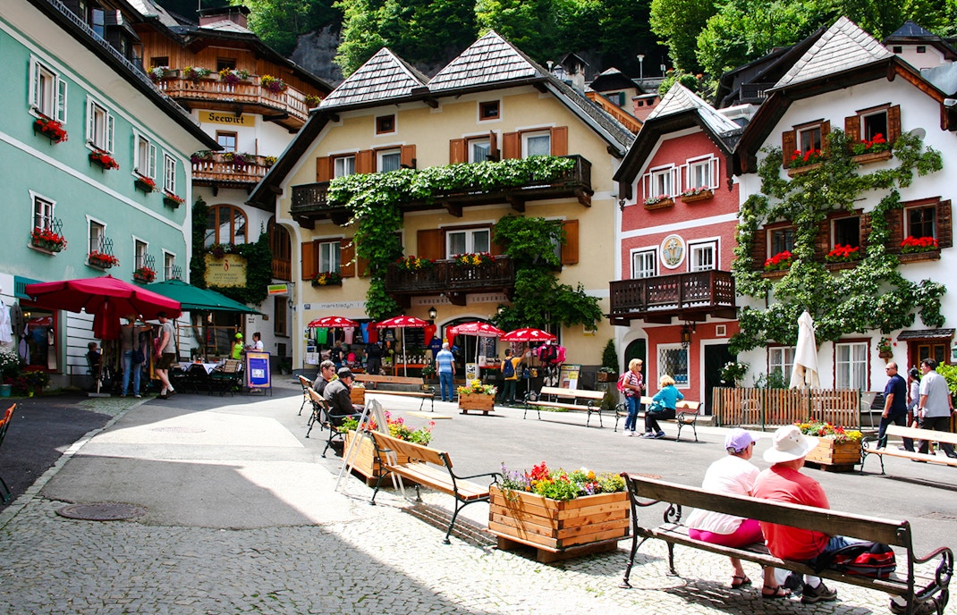 Hallstatt old town square with colorful buildings and people sitting on benches, Austria.